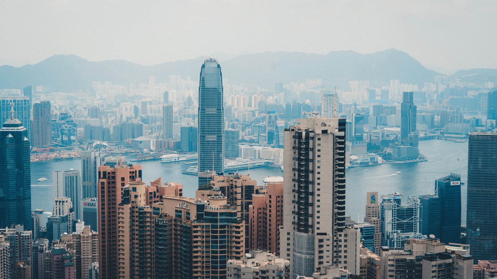 A cityscape of Hong Kong featuring skyscrapers and Victoria Harbor.